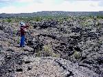 A hiker on shiny black basalt.