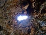 A tiny skylight in the ceiling of a cave