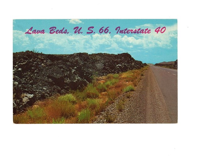 A 1960s-era postcard displays a two-lane highway lined on both sides with tall piles of jagged, black lava.  The words "Lava Beds, U.S. 66, Interstate 40" creates a banner across the top.