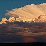 A thunderhead cloud fans out above a growing storm.