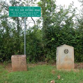 A sign and stone markers tell history of the San Antonio Road in Texas