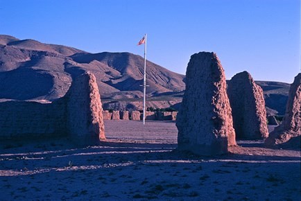 stone ruins of walls with a post and an american flag in the middle