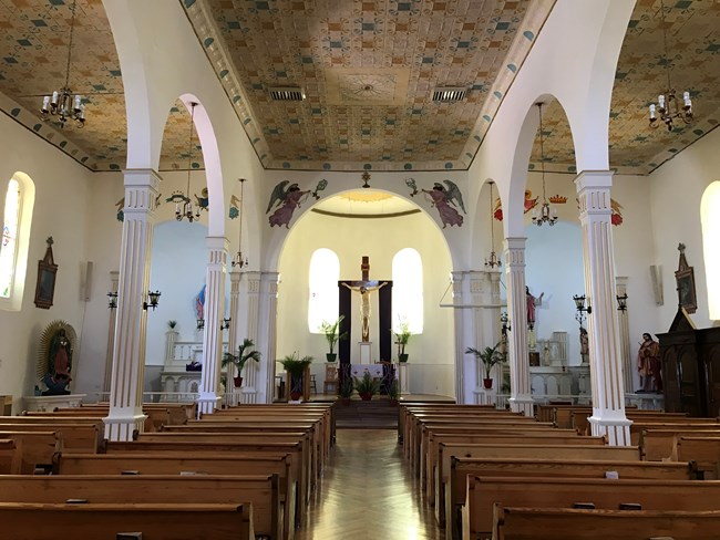 image of inside a chapel, with wooden seats and the altar