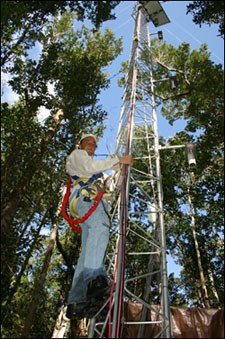 photo of a park scientist and an almost 90 ft tower that monitors the interactions of carbon in a mangrove community