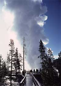 A small group of people watch Steamboat Geyser erupt