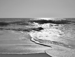 A black and white image of waves crashing on shore.