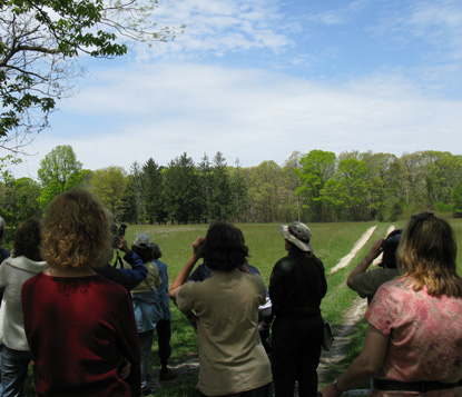 Group with binoculars look over field at William Floyd Estate.