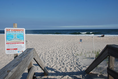 Sign along boardwalk to beach warns of rip current hazards.