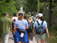 Group of hikers stroll down narrow walkway through Fire Island Community.