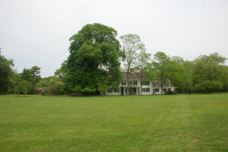 William Floyd Estate Grounds and Old Mastic House flanked by towering trees.