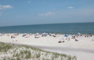 Ocean beach at Watch Hill with scattered sunbathers and umbrellas.