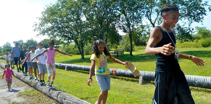 A group of kids walk along a wooden pole at Gateway National Recreation Area A group of kids walk along a wooden pole at Gateway National Recreation Area