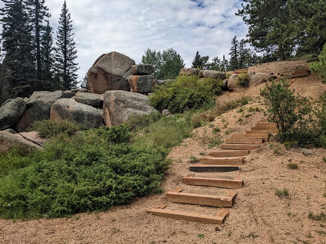 Wooden steps in the hillside next to large boulders
