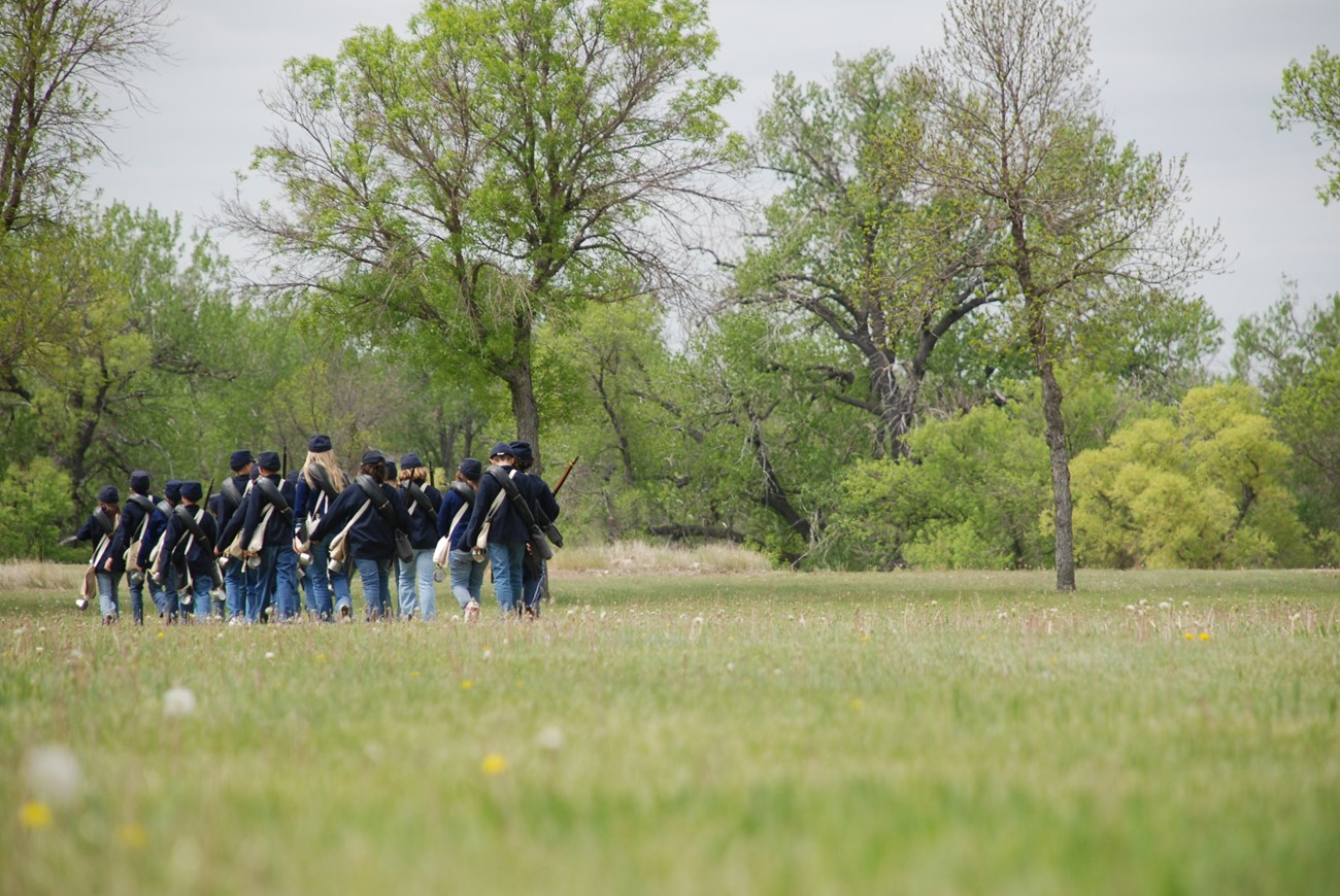 Students marching across a meadow during the Following the Guidon program.