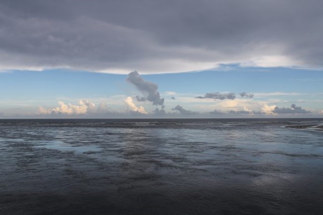 Atlantic Ocean with clouds above and along the horizon, seen from Matanzas Inlet bridge