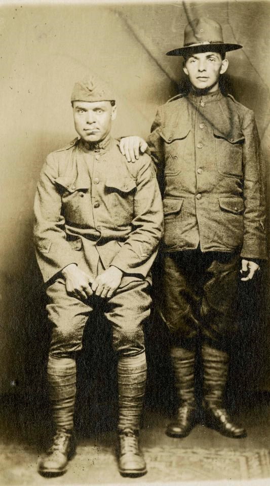 A black and white photograph of two World War I soldiers, one sitting and one standing. Each has a distorted face from needing facial reconstruction surgeries.