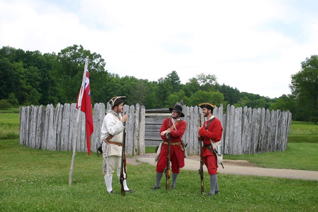 Three soldiers standing in front of the stockade