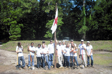The YCC Crew stands around the new flag pole at the earthworks.