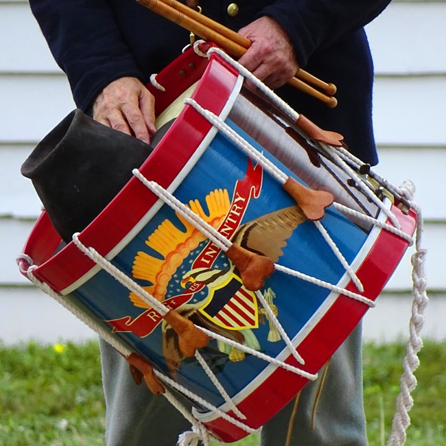View of an infantry drum held by a uniformed 19th century soldier at Fort Scott