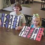 two children holding their Osage ribbon designs
