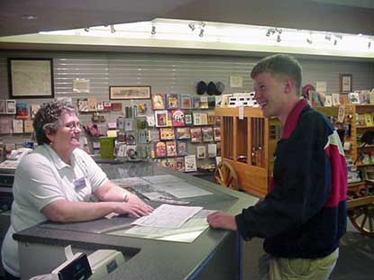 VIP at front desk talking to visitor.  Bookstore is in background