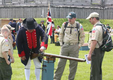 Uniformed Boy scouts examine 18th century weaponry under the supervision of a continental soldier