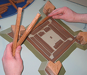 picture outline of a fort, a person's hands lying building blocks around the outline