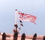a red and white striped flag with a British Union Jack in the corner flies in the breeze over the fort walls