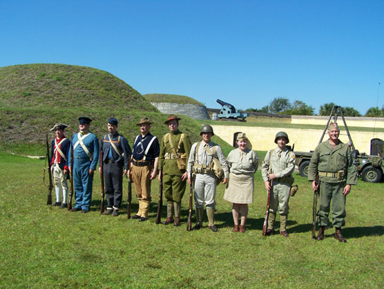 Nine people dressed as soldiers from the Revolutionary War through WWII.