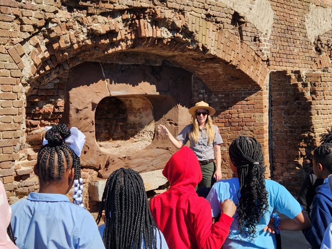A ranger speaks with a school group in front of the remains of a cannon embrasure