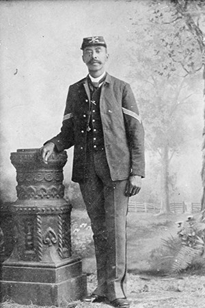 African American soldier standing in uniform with kepi and sack coat with sergeant's stripes