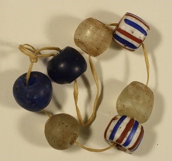 A string of round glass beads, two blue beads, three discolored clear beads, and two white beads with red and blue stripes.