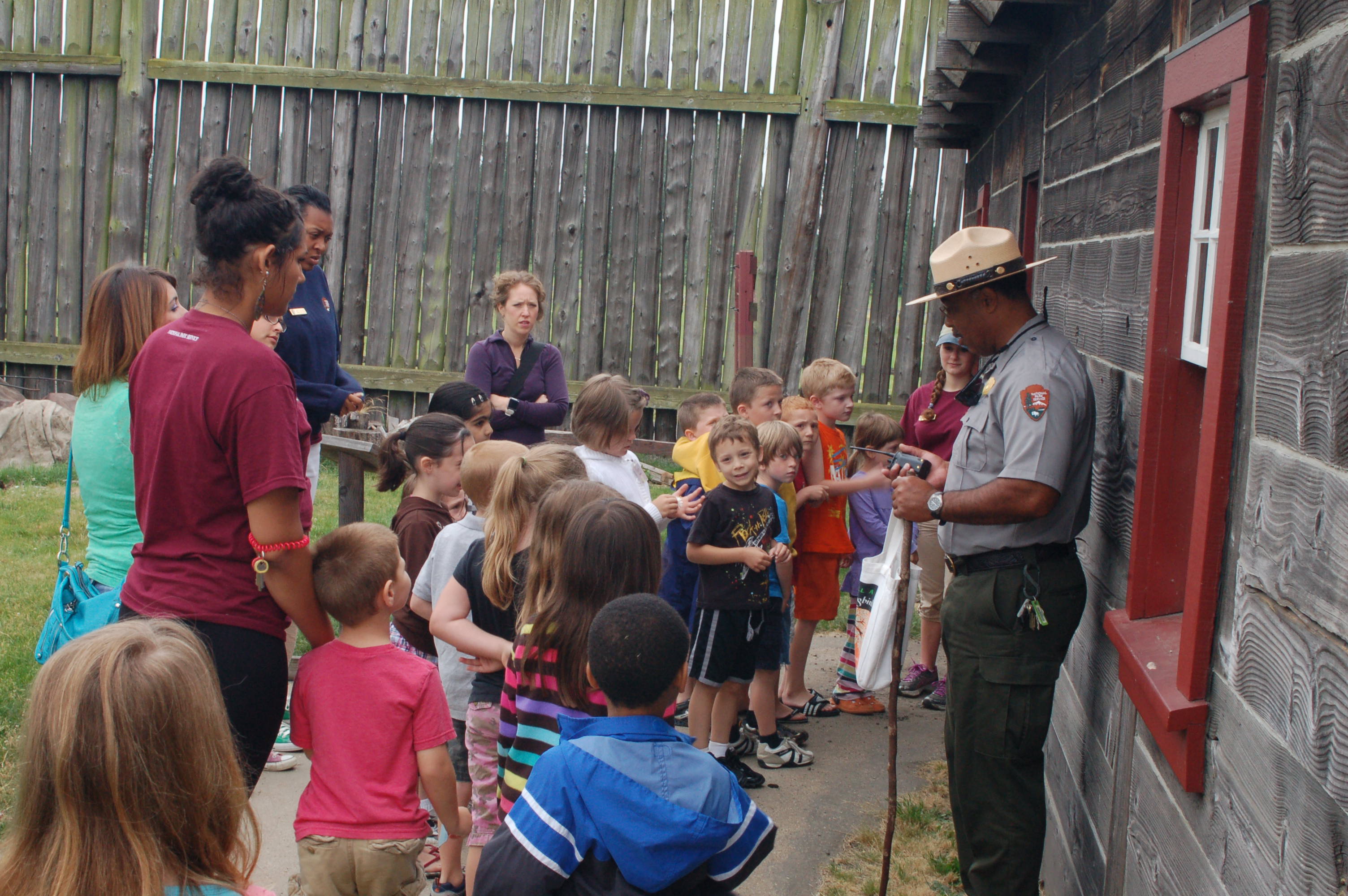 Group of kids stand outside blacksmith shop with park ranger
