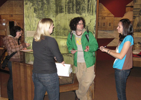four students take notes and observe the exhibits in the park's Visitor Center