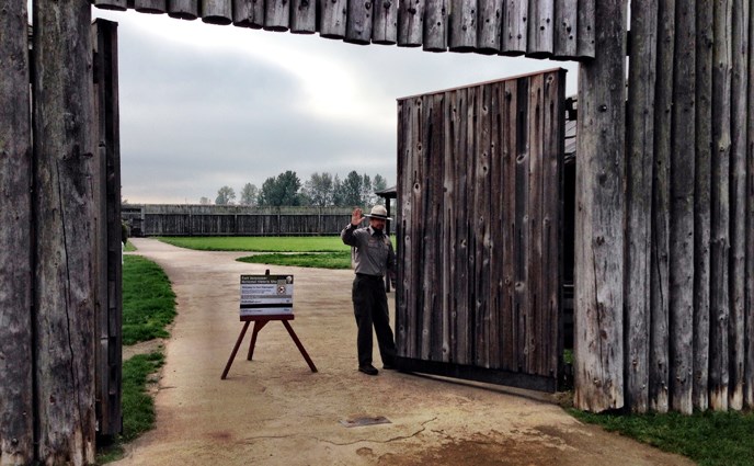 Image showing park ranger opening the main stockade gate at Fort Vancouver NHS and waving to welcome returning visitors.