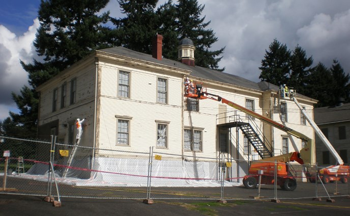 View of the Post Headquarters, Bldg 991, from the south, showing crews preparing it for painting.
