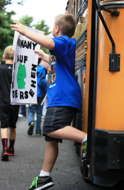 A third grade student disembarks the bus en route to the Children's Cultural Parade.