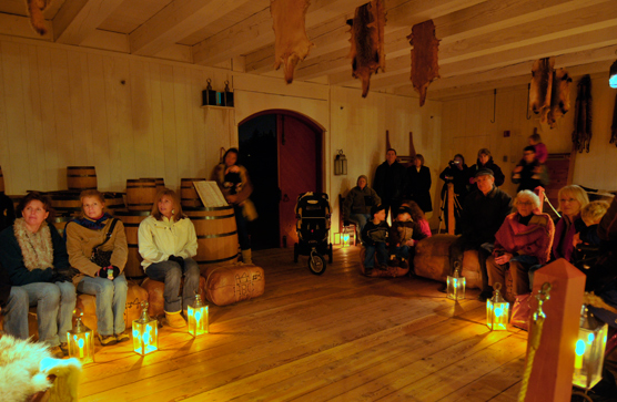 Lantern Tour participants sit and listen to a ranger talk in the Fur Store