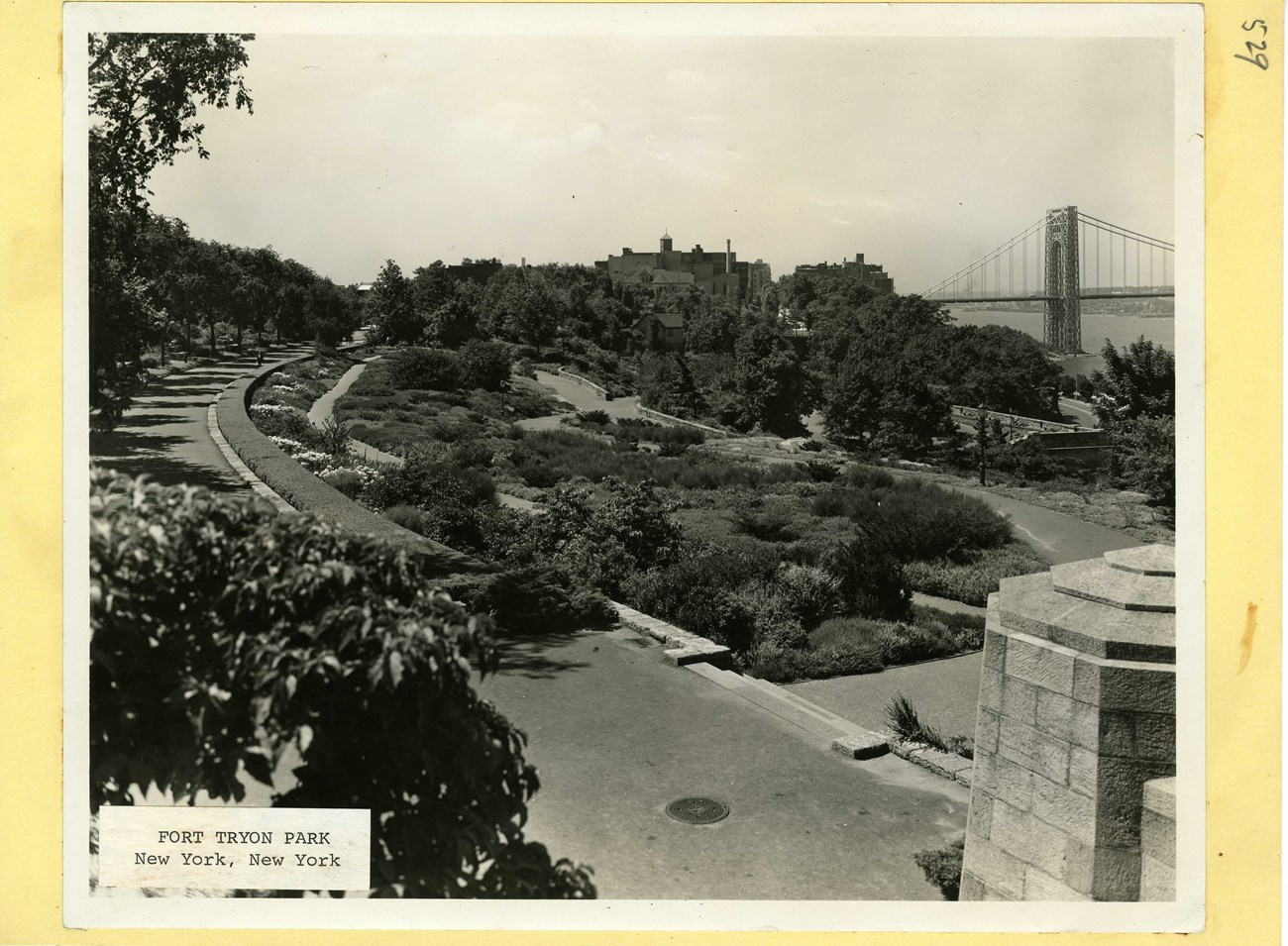 Black and white of park with river and bridge in distance.