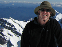 On a blue sky snow covered day, John Foley stands atop Mt. St. Helens