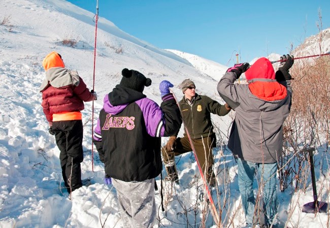A ranger and students conduct an activity outdoors in winter