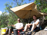 Resident Artist Mark Ross and Ranger Pete Christian get out of the sun under a tarp.