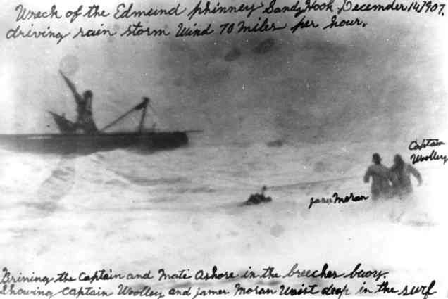 "Wreck of the Edmund J. Phinney Sandy Hook December 14, 1907. driving rain storm wind 70 miles per hour. Brin[g]ing the Captain and Mate ashore in the breeches buoy. Showing [USLSS] Captain Woolley and [USLSS] James Moran waist deep in the surf"