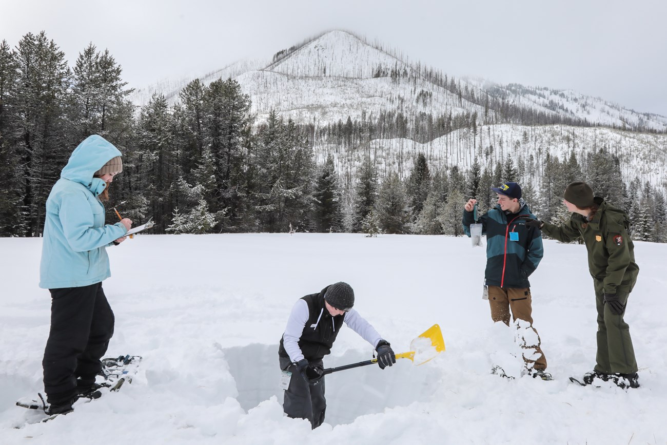 Students record measurements, dig a snowpit, and weigh snow with the help of a ranger.