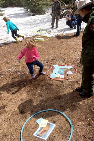Ranger stands by hoops on ground filled with documents as little girls run about