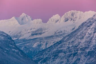 Pink sky sunset over snowy mountains.