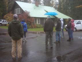 Students and park staff look at the West Lakes building on a rainy day.