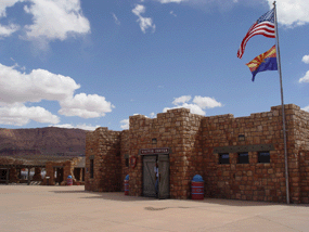A rock building with wooden doors flies the American and Arizona flags.