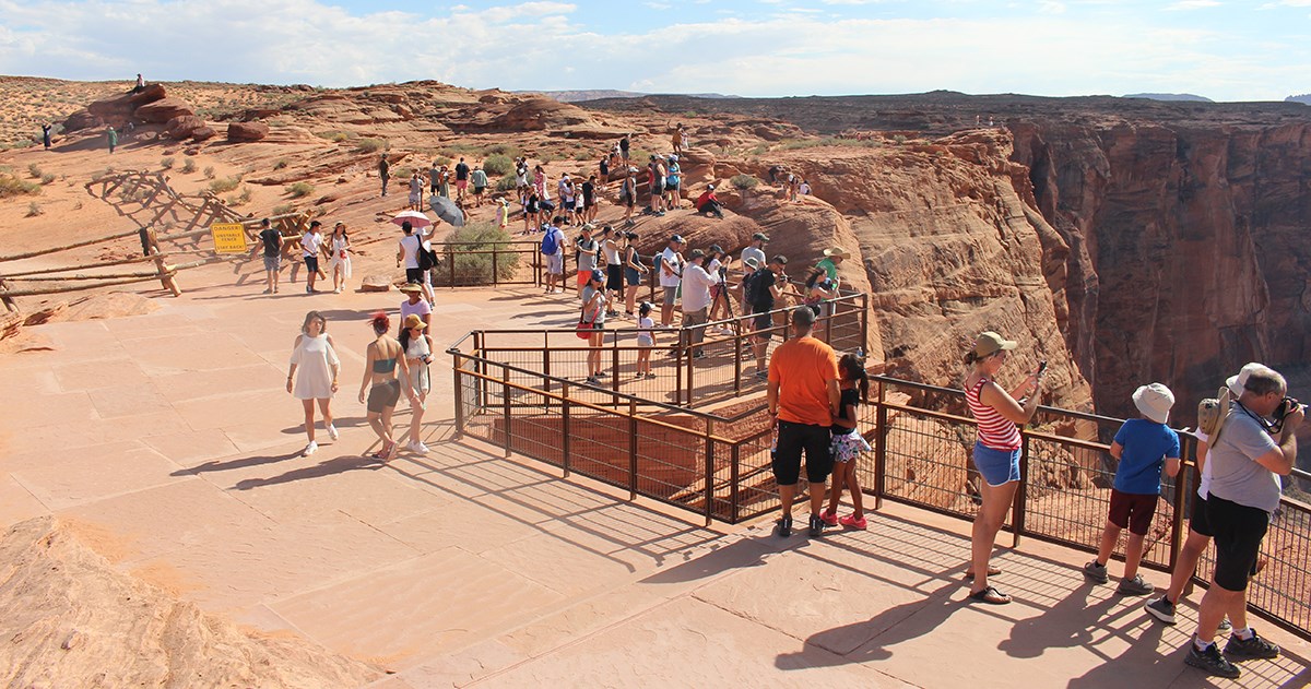 Large group of visitors on flagstone viewing platform at edge of canyon
