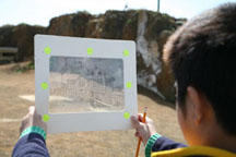 A student holding a Magic Window  transparency at Point Bonita.